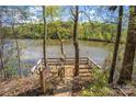 Picturesque lake view from wooded property, featuring a wooden dock, natural landscaping, and calm waters at 902 Cornelius Rd, Mooresville, NC 28117