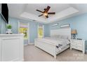 Serene bedroom with a tray ceiling, a ceiling fan, ample natural light, and elegant white furniture at 114 Rolling Stone Ct, Mooresville, NC 28117