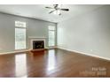 Open living room featuring hardwood floors, fireplace, ceiling fan, and large windows for natural light at 13417 Krislyn Woods Pl, Charlotte, NC 28278