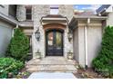 Close-up of the stately stone entryway and black wrought iron doors, framed by mature landscaping at 20428 Island Forest Dr, Cornelius, NC 28031