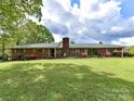 Charming brick home featuring a lush green lawn and meticulously landscaped front yard with mature trees at 225 Enwood Dr, Charlotte, NC 28214