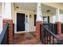 Inviting front porch with black rocking chairs, brick accents and decorative columns enhancing the curb appeal at 5015 Drake Pond Ln, Rock Hill, SC 29732