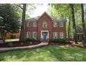Charming two-story red brick home featuring a lush green lawn and mature trees at 6910 Green Turtle Dr, Charlotte, NC 28210
