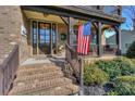 Inviting front porch with brick steps, American flag and a beautifully decorated front door at 10643 Rippling Stream Nw Dr, Concord, NC 28027