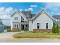 Charming two-story gray home with brick accents, an inviting front porch, and lush landscaping at 139 Little Indian Loop, Mooresville, NC 28117