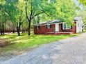 Charming brick home featuring a cozy front porch, black shutters and lovely, mature landscaping at 1780 Short St, Mount Pleasant, NC 28124