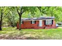 Charming brick home featuring a cozy front porch, black shutters and lovely, mature landscaping at 1780 Short St, Mount Pleasant, NC 28124