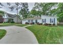A view of the home's exterior, featuring a well-kept lawn, driveway, and lush surrounding trees at 22025 Torrence Chapel Rd, Cornelius, NC 28031