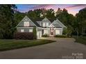 Charming two-story home with gray siding, white trim, a red door, and well-maintained landscaping at sunset at 6743 Fox Ridge Cir, Davidson, NC 28036