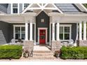 Inviting front porch featuring stone pillars, white columns, a red door with wreath, and chairs at 6743 Fox Ridge Cir, Davidson, NC 28036