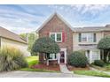Charming brick townhome featuring a well-manicured front yard and inviting entrance with a red door and bright shutters at 8221 Pineville Matthews Rd # A, Charlotte, NC 28226