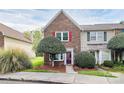 Charming brick townhome featuring a well-manicured front yard and inviting entrance with a red door and bright shutters at 8221 Pineville Matthews Rd # A, Charlotte, NC 28226