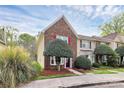Charming two-story townhome with a well-maintained lawn, mature landscaping, and a brick facade with red shutters at 8221 Pineville Matthews Rd # A, Charlotte, NC 28226