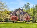 Charming brick home with a well-manicured front lawn, mature trees, and landscape featuring brick and stone accents at 1012 Shippon Ln, Waxhaw, NC 28173
