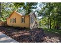 Cozy waterfront home with brown siding, white window trim, stone foundation, and mature trees at 119 Harbor Ln, Mount Gilead, NC 27306