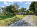 Home's exterior featuring a gravel driveway, lush lawn, and welcoming facade at 140 Misty Ln, Rockwell, NC 28138