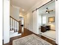 Elegant hallway featuring hardwood floors, a staircase, and an office featuring a sliding barn door at 1550 Matthew Mcclure Cir, Davidson, NC 28036