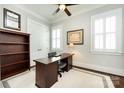 Well-lit office with a dark wood desk, neutral walls, and framed pictures, with a ceiling fan at 1550 Matthew Mcclure Cir, Davidson, NC 28036