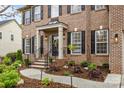 Inviting brick home entrance with black door, meticulous landscaping, and stone walkway at 1809 Robbins Meadows Dr, Waxhaw, NC 28173