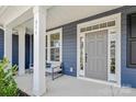 Inviting front porch with white columns, seating, and a gray front door with sidelights and transom window at 235 Boxelder Rd, Clover, SC 29710