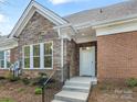 Charming home exterior featuring brick and stone accents, a covered entrance, and manicured landscaping at 2874 Bellasera Way, Matthews, NC 28105