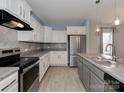 Stylish kitchen features white cabinets, gray countertops, stainless steel appliances, and wood-look flooring at 317 Contentment Dr, Locust, NC 28097