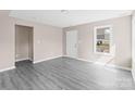 Bright living room featuring gray wood-look floors and several windows for natural light. Backdoor on right wall at 8722 Moody Rd, Charlotte, NC 28215