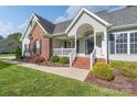 Inviting front porch featuring brick stairs, white railings and columns, and an arched entryway offering curb appeal at 921 Snow Prince Ln, York, SC 29745