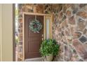 Elegant front door with stone surround, wreath, and potted plant for a welcoming entrance at 2001 Cramer Place Ct, Cramerton, NC 28032
