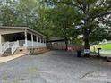 Home exterior with covered porch and gravel driveway surrounded by mature trees at 207 Deer Park Rd, Mount Gilead, NC 27306