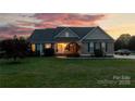 Attractive home with stone accents, manicured lawn, and inviting entryway at dusk at 234 Deal Estate Dr, China Grove, NC 28023