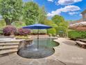 Beautiful backyard pool with a built-in spa, stone accents, mature landscaping, and a serene atmosphere at 2553 Fallbrook Nw Pl, Concord, NC 28027