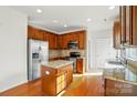 Well-equipped kitchen with stainless steel appliances, granite countertops, wooden cabinets, and hardwood floors at 3619 Grove Creek Pond Sw Dr, Concord, NC 28027