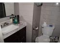 Compact bathroom featuring a dark vanity with white marble countertops and a tiled wall at 5915 Bluebonnet Rd, Charlotte, NC 28212