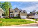 Charming two-story home boasts well-manicured lawn, brick accents, and attached garage under bright blue skies at 609 Tysons Forest Dr, Rock Hill, SC 29732