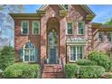 Brick facade home featuring an arched entrance, manicured landscaping, and a welcoming staircase at 7117 Chadwyck Farms Dr, Charlotte, NC 28226