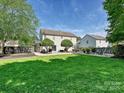 Expansive backyard featuring a lush lawn, stone patio with seating, and mature trees creating a private oasis at 8140 Laurel Run Dr, Charlotte, NC 28269