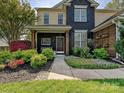 Inviting home featuring a landscaped front yard with vibrant flowers and greenery, leading to a cozy covered porch at 8140 Laurel Run Dr, Charlotte, NC 28269