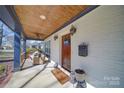 Inviting front porch with wood ceiling, white brick siding, and cozy seating area at 1009 Leigh Ave, Charlotte, NC 28205