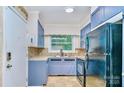 Well-lit kitchen boasts blue cabinets, stainless steel sink, and modern appliances, offering functionality and style at 1409 Sherwood Dr, Kannapolis, NC 28081