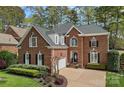 Elegant brick home with a three-car garage, complemented by professional landscaping and a circular driveway at 18418 Turnberry Ct, Davidson, NC 28036