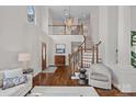 Bright, open foyer featuring hardwood floors, a staircase, and a view into the adjacent living spaces at 18418 Turnberry Ct, Davidson, NC 28036