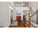 Grand foyer with hardwood floors, a staircase, and a statement cabinet that create a welcoming entrance at 18418 Turnberry Ct, Davidson, NC 28036
