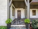 Inviting covered front porch with stone floors, decorative columns, and an ornate wooden door at 2030 Radcliffe Ave, Charlotte, NC 28207