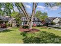 Beautifully landscaped front yard with a mature tree in front of a gray brick home with dormer windows at 2909 Park Rd, Charlotte, NC 28209