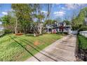 View of a gray brick home and driveway through mature trees with a grass yard and well manicured landscaping at 2909 Park Rd, Charlotte, NC 28209