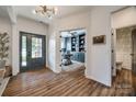 Elegant foyer featuring hardwood floors, a modern chandelier, and views into the home office and powder room at 4032 Wild Turkey Ln, Indian Land, SC 29707