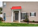 Close-up of front door with red accent roof showing shutters, siding, and manicured lawn at 4133 Carl Parmer Dr, Harrisburg, NC 28075
