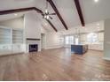 Open living area featuring exposed ceiling beams, hardwood floors, fireplace and kitchen island at 5604 Unionville Rd, Monroe, NC 28110