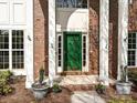 Inviting green front door with white columns, brick accents, and 'Welcome' potted plants for a warm entry at 6112 Swanston Dr, Charlotte, NC 28269